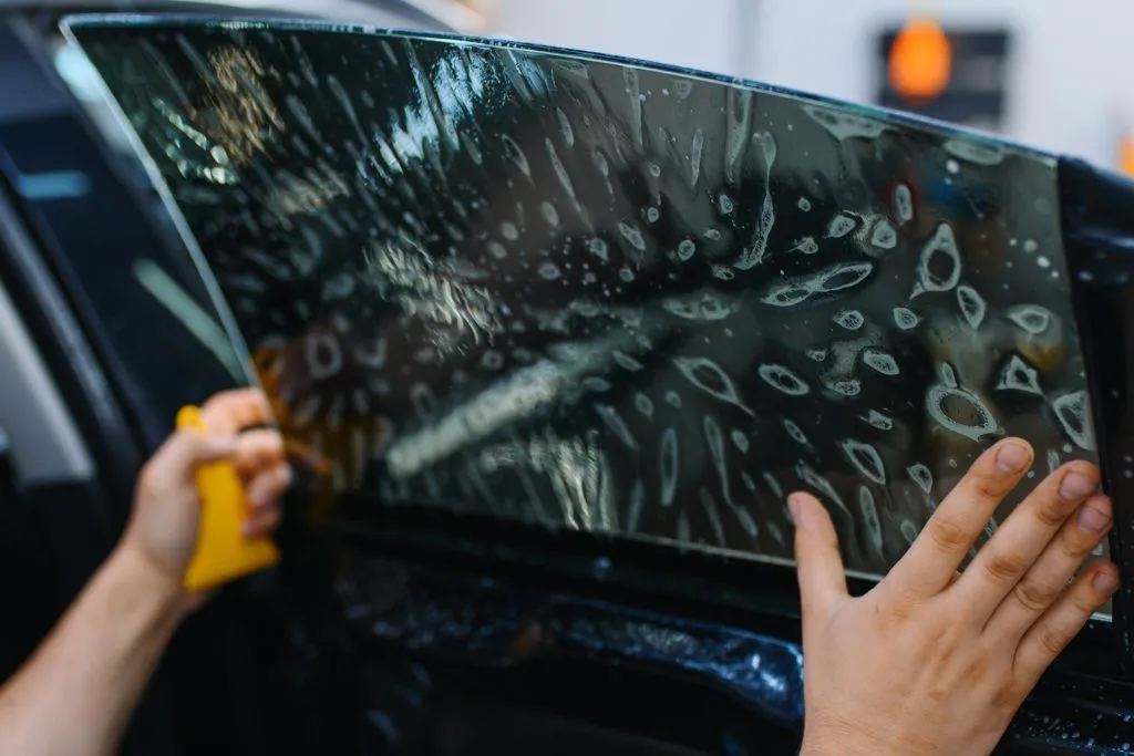 image3jpg | Blue Star Auto Salon Person cleaning a car window with a yellow sponge, water smears on the glass.
