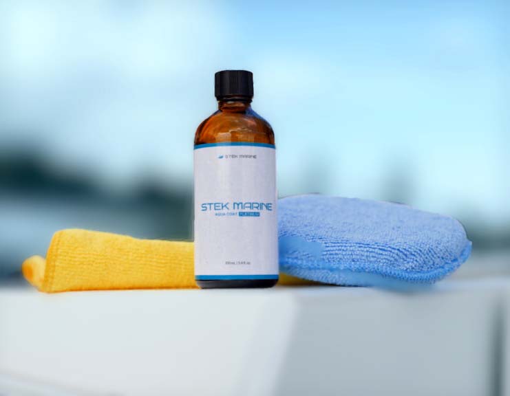Bottle of STEK MARINE cleaner with yellow and blue microfiber towels on a white surface.