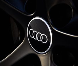 Close-up of an Audi logo on a black alloy wheel.