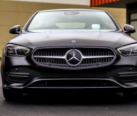 Front view of a dark gray Mercedes-Benz parked, featuring the distinctive grille and emblem.