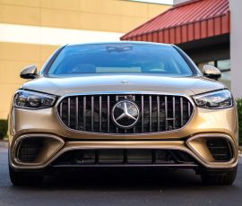 Front view of a gold Mercedes-Benz SUV parked outdoors, showcasing the signature grille and badge with a dealership watermark in the corner.