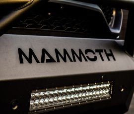 Close-up of a rugged vehicle front with 'MAMMOTH' branding and a chrome LED light bar; Blue Star Autosalon logo in corner.