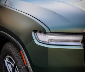 Front-left close-up of a metallic green SUV showing headlight, fender, and wheel with a watermark reading BLUE STAR AUTOSALON