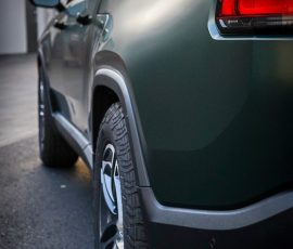 Green SUV rear quarter panel and wheel, close-up at a dealership, Bluestar Autosalon watermark.